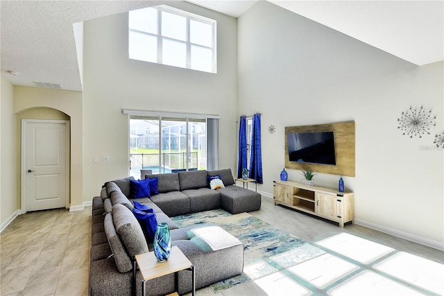 8974 Cabot Cliffs Dr, Davenport, FL 33896 - living room with arched walkways, plenty of natural light, a towering ceiling, and baseboards