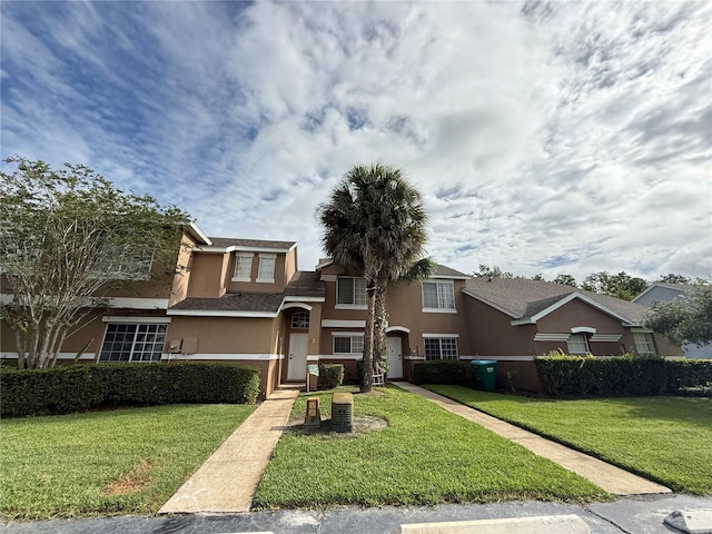 traditional-style house featuring stucco siding and a front lawn