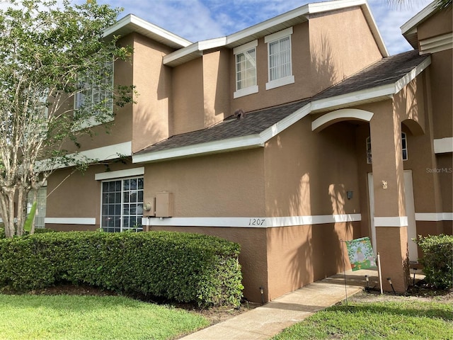 view of home's exterior with stucco siding and a shingled roof