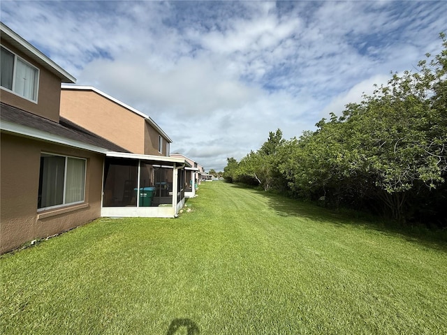 view of green lawn with a sunroom