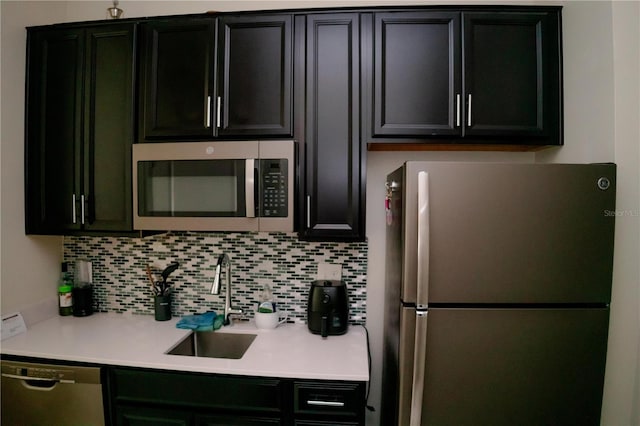 153 Taft Dr, Davenport, FL 33837 - kitchen with stainless steel appliances, a sink, dark cabinetry, light countertops, and tasteful backsplash