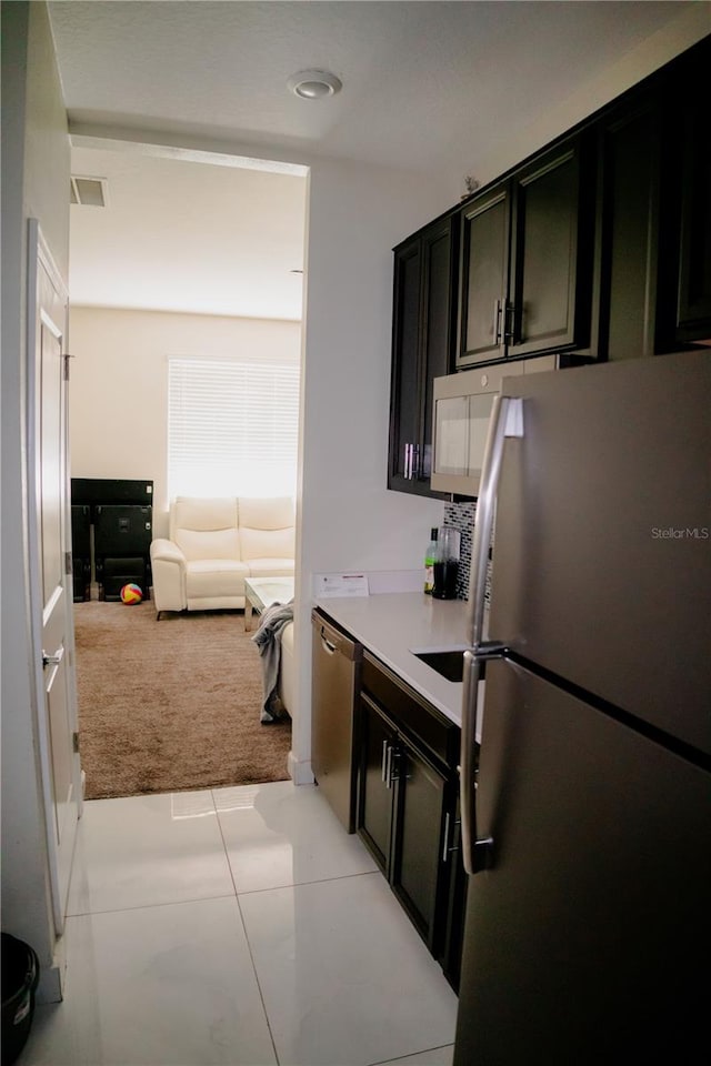 153 Taft Dr, Davenport, FL 33837 - kitchen featuring appliances with stainless steel finishes, light colored carpet, dark cabinetry, open floor plan, and light countertops