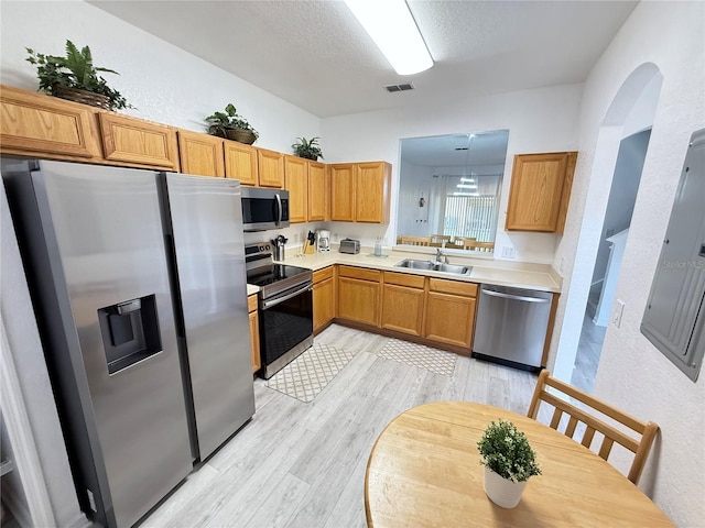 615 Terra Lago St, Davenport, FL 33897 - kitchen featuring stainless steel appliances, light countertops, light wood-type flooring, electric panel, and a textured ceiling