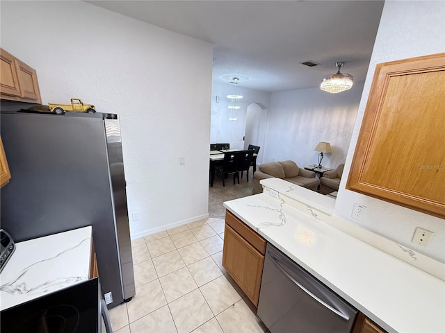 324 Palermo St, Davenport, FL 33897 - kitchen featuring stainless steel appliances, arched walkways, light countertops, light tile patterned floors, and brown cabinets