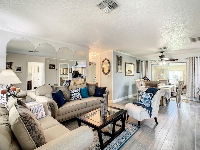 624 Royal Palm Dr, Kissimmee, FL 34743 - living room with a textured ceiling, arched walkways, a ceiling fan, light wood finished floors, and ornamental molding