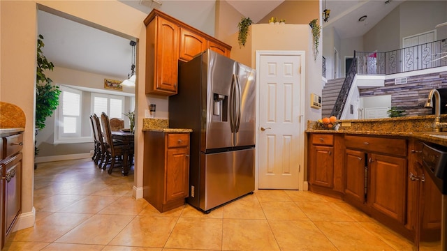 2851 Granada Blvd, Kissimmee, FL 34746 - kitchen with stainless steel refrigerator with ice dispenser, brown cabinetry, dark stone countertops, light tile patterned floors, and lofted ceiling