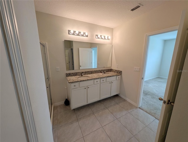 2479 White Lilly Dr, Kissimmee, FL 34747 - full bathroom with double vanity, tile patterned floors, a shower stall, a textured ceiling, and baseboards
