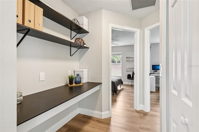 2700 Palm Isle Way, Orlando, FL 32829 - hall featuring a desk, wood finished floors, baseboards, and a textured ceiling