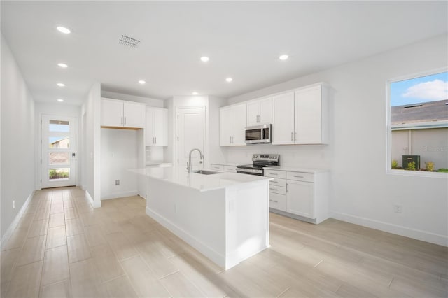 9127 Players Dr, Weeki Wachee, FL 34613 - kitchen with stainless steel appliances, white cabinetry, a center island with sink, recessed lighting, and light countertops