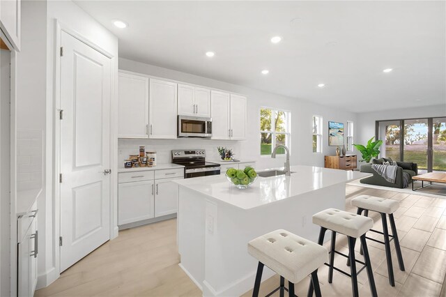 9127 Players Dr, Weeki Wachee, FL 34613 - kitchen with appliances with stainless steel finishes, recessed lighting, a breakfast bar, a center island with sink, and white cabinetry