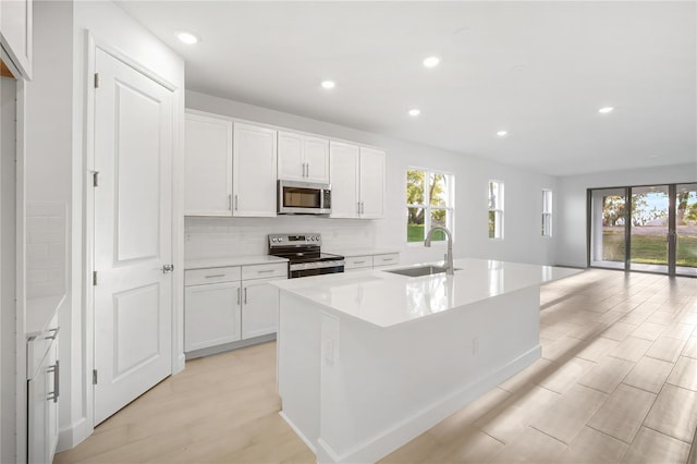 9127 Players Dr, Weeki Wachee, FL 34613 - kitchen with appliances with stainless steel finishes, recessed lighting, light wood-style floors, a kitchen island with sink, and white cabinets