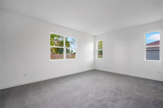 9127 Players Dr, Weeki Wachee, FL 34613 - empty room featuring plenty of natural light and dark carpet