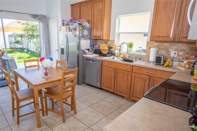 2268 Victoria Falls Dr, Orlando, FL 32824 - kitchen featuring appliances with stainless steel finishes, brown cabinetry, decorative backsplash, and healthy amount of natural light