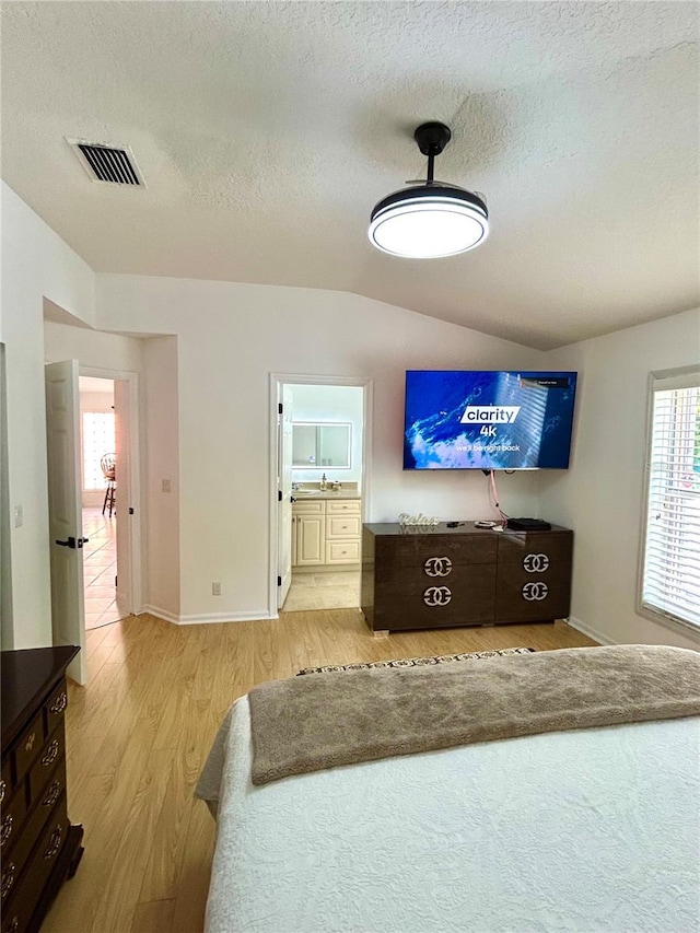 1084 Aspri Way, Riviera Beach, FL 33418 - bedroom with wood finished floors, a textured ceiling, lofted ceiling, a sink, and ensuite bathroom