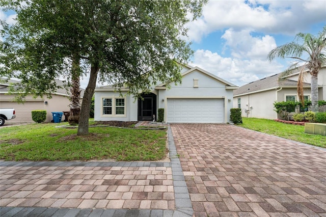 205 Lakeshore Dr, Davenport, FL 33837 - view of front facade with decorative driveway, a garage, a front yard, and stucco siding