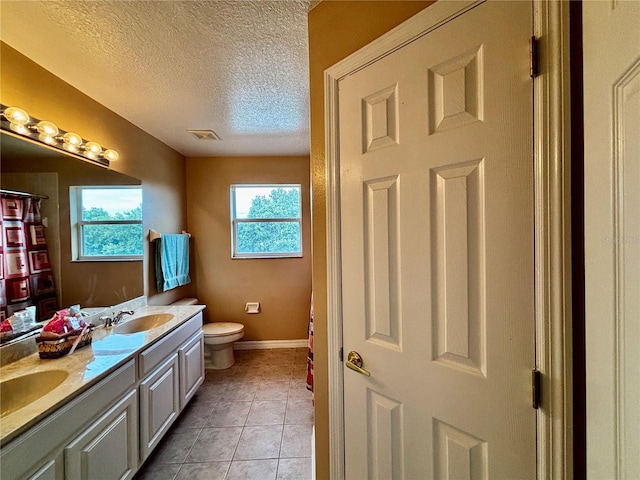4368 Fox Glen Loop, Kissimmee, FL 34746 - bathroom with double vanity, toilet, a textured ceiling, baseboards, and tile patterned flooring