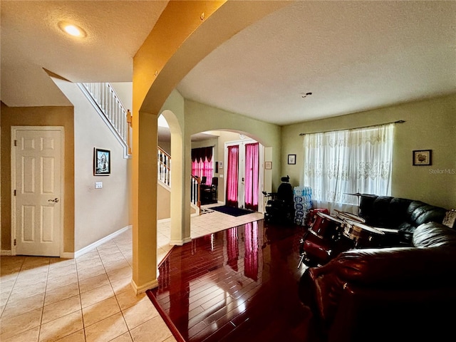 4368 Fox Glen Loop, Kissimmee, FL 34746 - living area with arched walkways, a textured ceiling, light tile patterned floors, stairs, and baseboards