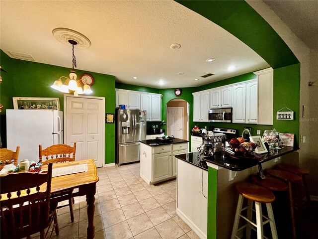 4368 Fox Glen Loop, Kissimmee, FL 34746 - kitchen featuring stainless steel appliances, arched walkways, a peninsula, white cabinetry, and dark countertops