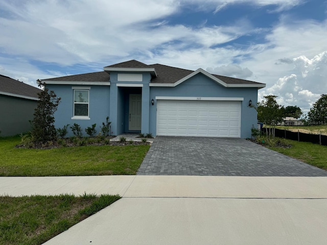 522 Feltrim Manor Rd, Haines City, FL 33844 - view of front of house featuring stucco siding, decorative driveway, an attached garage, a front yard, and a shingled roof