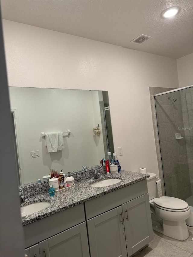 522 Feltrim Manor Rd, Haines City, FL 33844 - bathroom featuring double vanity, toilet, a shower stall, tile patterned floors, and a textured ceiling
