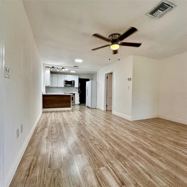 1615 NE 9th St, Ocala, FL 34470 - unfurnished living room featuring light wood-type flooring, baseboards, ceiling fan, and a textured ceiling