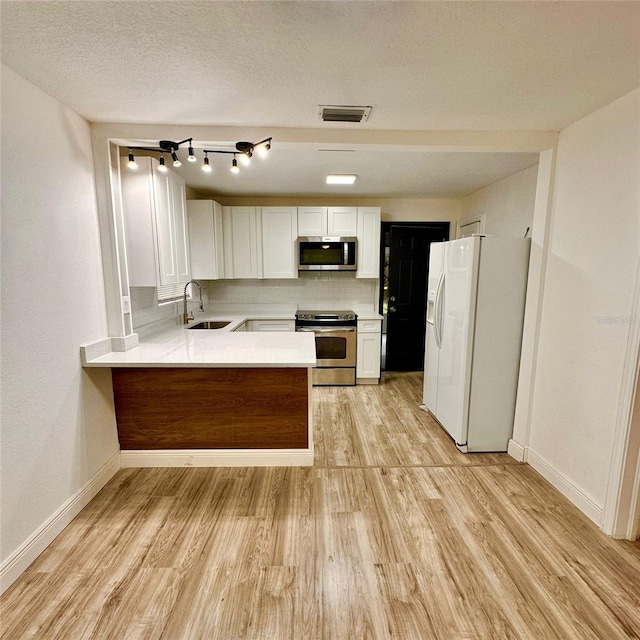1615 NE 9th St, Ocala, FL 34470 - kitchen featuring appliances with stainless steel finishes, a sink, light wood-type flooring, a peninsula, and light countertops