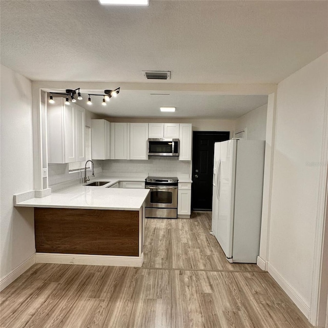 1615 NE 9th St, Ocala, FL 34470 - kitchen featuring appliances with stainless steel finishes, a peninsula, light wood finished floors, baseboards, and a textured ceiling