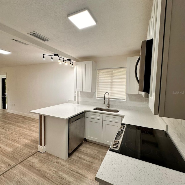 1615 NE 9th St, Ocala, FL 34470 - kitchen featuring appliances with stainless steel finishes, a sink, a peninsula, decorative backsplash, and light countertops