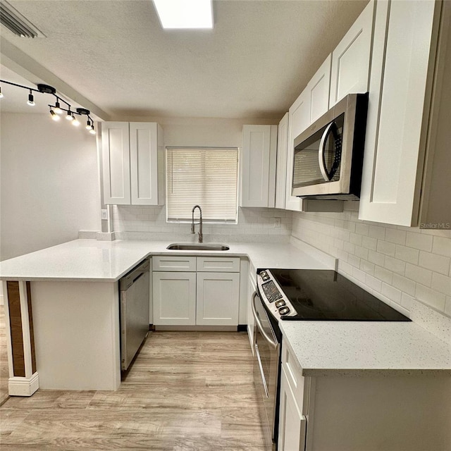 1615 NE 9th St, Ocala, FL 34470 - kitchen featuring appliances with stainless steel finishes, a sink, a peninsula, light wood finished floors, and backsplash