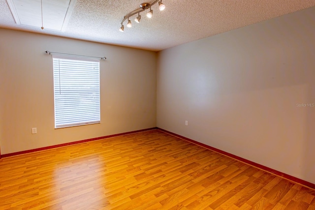 3267 Villa Way Cir, Saint Cloud, FL 34769 - unfurnished room featuring light wood-style floors, a textured ceiling, attic access, track lighting, and baseboards