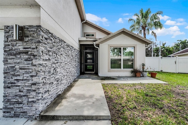 2561 Montego Bay Blvd, Kissimmee, FL 34746 - property entrance with stucco siding, a patio area, a gate, and stone siding