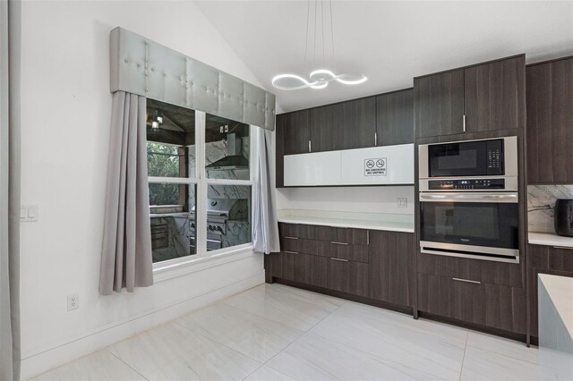 2561 Montego Bay Blvd, Kissimmee, FL 34746 - kitchen with stainless steel oven, black microwave, dark brown cabinets, light countertops, and a chandelier