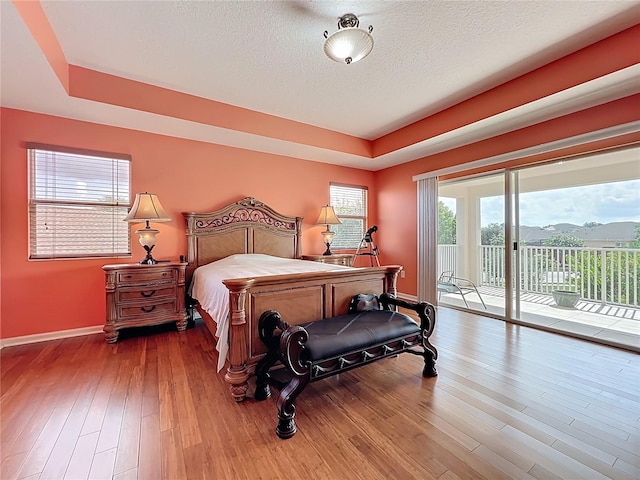 16072 Shasta St, Clermont, FL 34714 - bedroom with baseboards, access to exterior, wood finished floors, a raised ceiling, and a textured ceiling