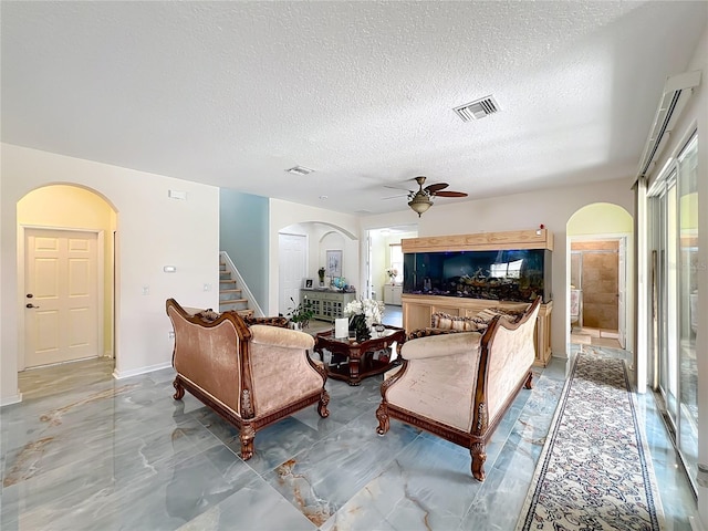 16072 Shasta St, Clermont, FL 34714 - living area featuring arched walkways, a ceiling fan, stairway, a textured ceiling, and baseboards