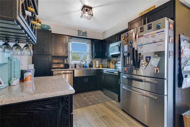 2 S Lavon Ave, Kissimmee, FL 34741 - kitchen with stainless steel appliances, light wood-style flooring, a sink, and light stone counters