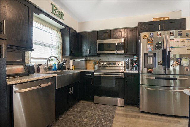 2 S Lavon Ave, Kissimmee, FL 34741 - kitchen with appliances with stainless steel finishes, light countertops, tasteful backsplash, light wood finished floors, and a sink
