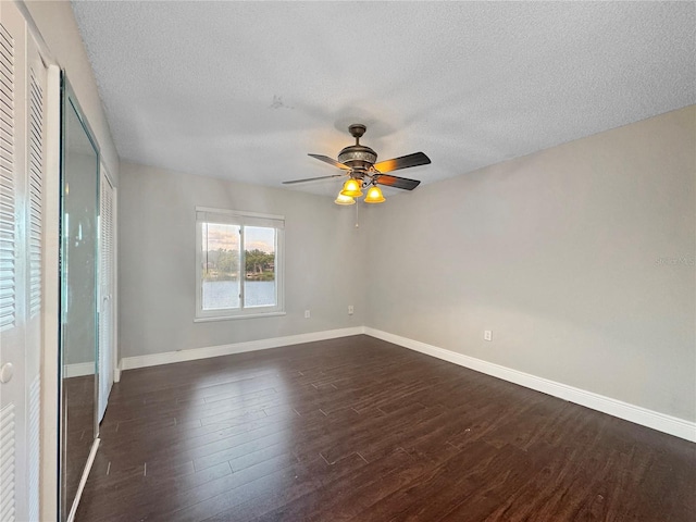 626 Orange Dr Unit 243, Altamonte Springs, FL 32701 - unfurnished bedroom with dark wood-type flooring, a textured ceiling, baseboards, two closets, and a ceiling fan