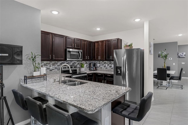 2838 Common Crane Ct, Harmony, FL 34773 - kitchen featuring stainless steel appliances, a sink, a peninsula, a kitchen breakfast bar, and dark brown cabinets