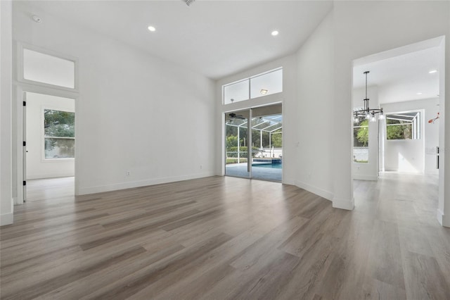 5254 Mill Stream Dr, Saint Cloud, FL 34771 - empty room with plenty of natural light, a chandelier, light wood-style flooring, a towering ceiling, and recessed lighting