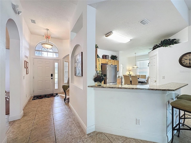 107 Amaca Ln, Davenport, FL 33897 - entryway featuring a textured ceiling, arched walkways, healthy amount of natural light, and light tile patterned floors
