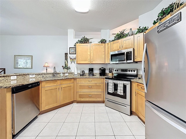 107 Amaca Ln, Davenport, FL 33897 - kitchen featuring stainless steel appliances, a peninsula, light brown cabinets, light stone counters, and a textured ceiling