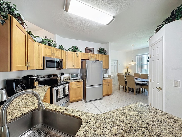107 Amaca Ln, Davenport, FL 33897 - kitchen with appliances with stainless steel finishes, a textured ceiling, light tile patterned flooring, pendant lighting, and light stone counters