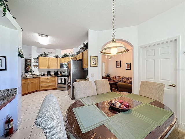 107 Amaca Ln, Davenport, FL 33897 - dining area with light tile patterned flooring, arched walkways, a textured ceiling, and a chandelier