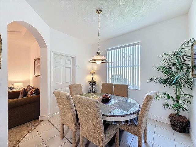107 Amaca Ln, Davenport, FL 33897 - dining room with light tile patterned flooring, arched walkways, and a textured ceiling