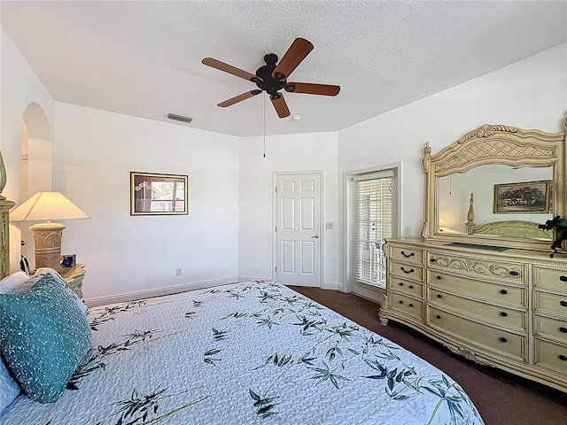 107 Amaca Ln, Davenport, FL 33897 - bedroom with dark colored carpet, a ceiling fan, arched walkways, and a textured ceiling