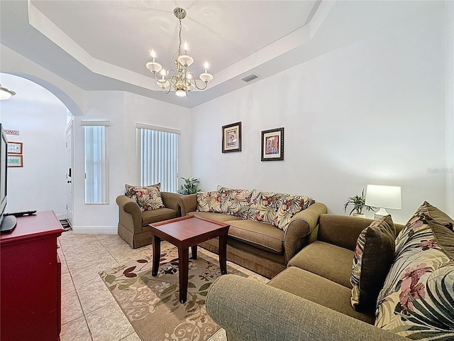 107 Amaca Ln, Davenport, FL 33897 - living room featuring arched walkways, a chandelier, a tray ceiling, and light tile patterned floors