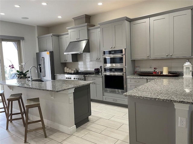 8919 Lakeshore Pointe Dr, Winter Garden, FL 34787 - kitchen with under cabinet range hood, appliances with stainless steel finishes, gray cabinets, tasteful backsplash, and recessed lighting