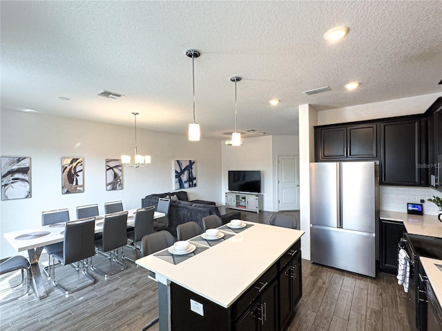 4736 Tribute Trl, Kissimmee, FL 34746 - kitchen featuring freestanding refrigerator, dark wood-style flooring, light countertops, a textured ceiling, and tasteful backsplash