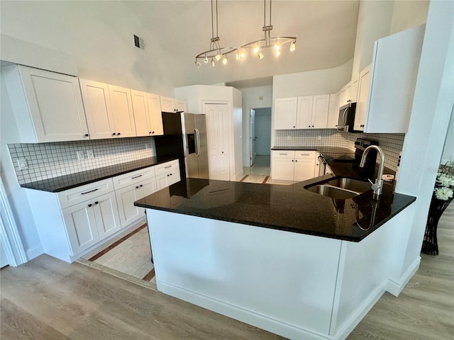 2356 Chadwick Cir, Kissimmee, FL 34746 - kitchen featuring appliances with stainless steel finishes, a sink, high vaulted ceiling, decorative backsplash, and a peninsula
