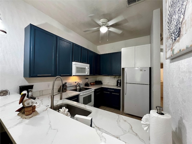 1106 Gran Bahama Blvd Unit 1106, Davenport, FL 33897 - kitchen with white appliances, light stone counters, ceiling fan, blue cabinets, and a peninsula